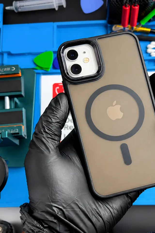 A repaired iPhone 12 in a technician’s gloved hand over the MobiDokta repair mat